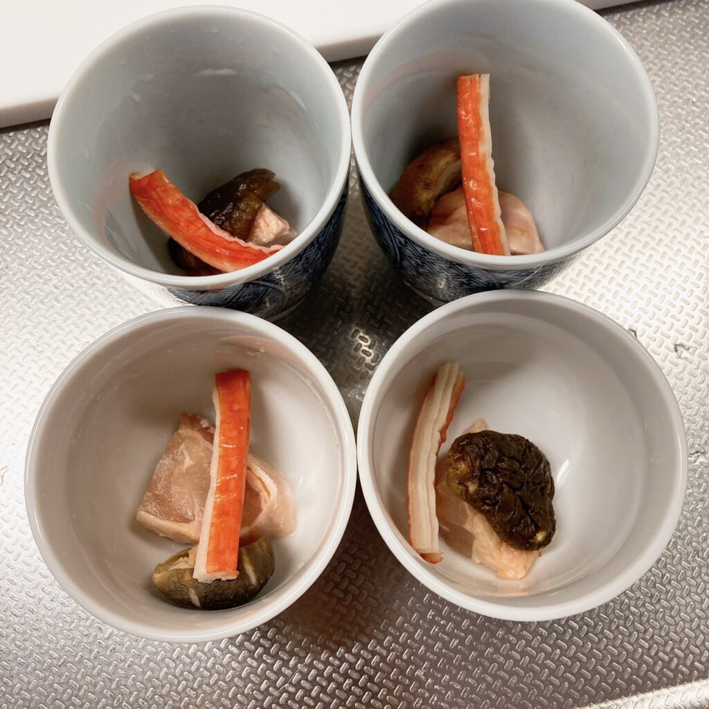 茶碗蒸しの器に入っているカニカマ・鶏肉・干しシイタケ