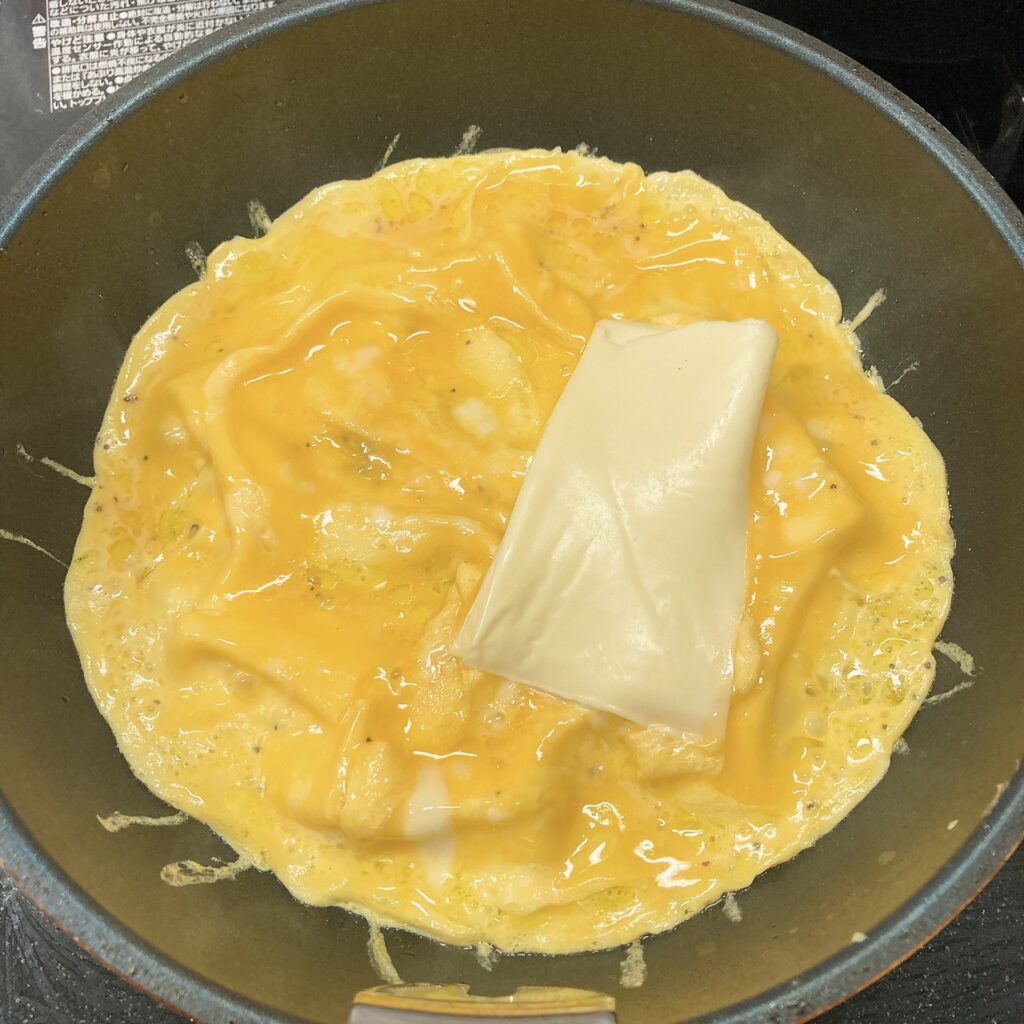 チーズをのせたオムレツを焼いているフライパン