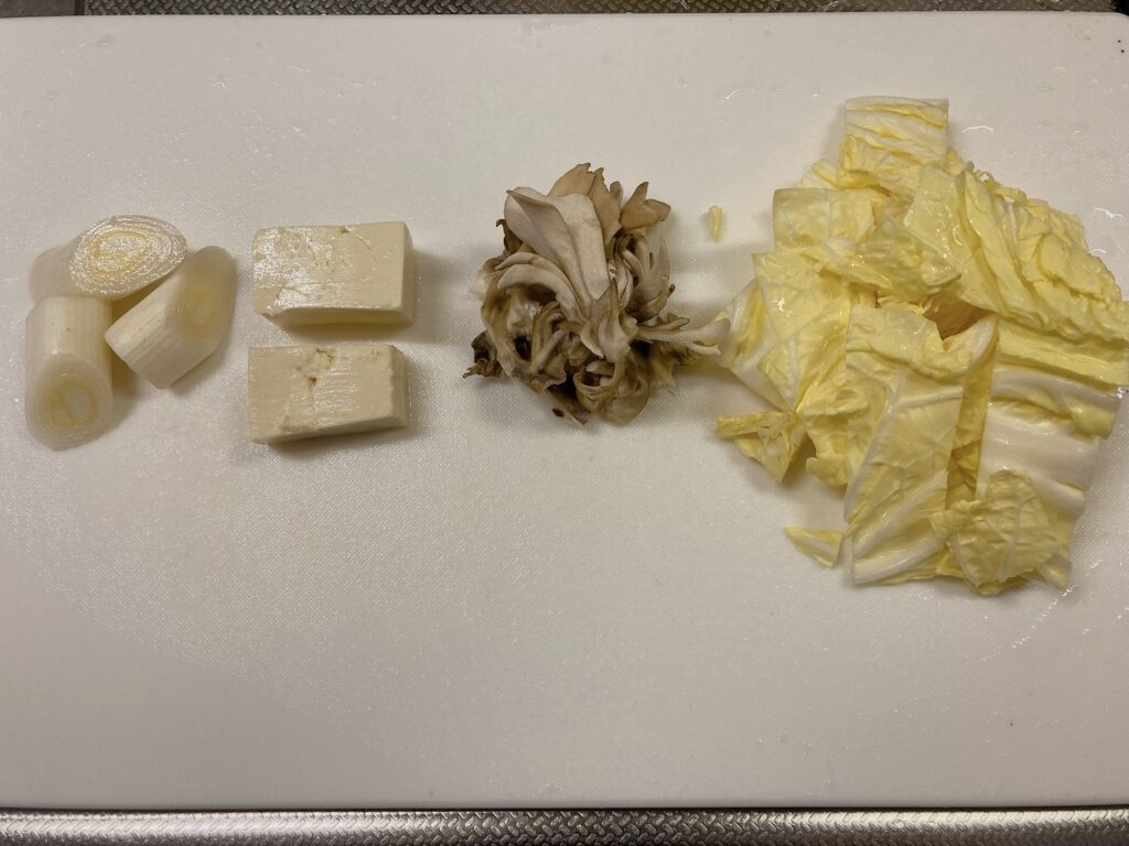 1口サイズに斜めに切った長ネギ、1口サイズに切った豆腐、さいてバラバラにしたまいたけ、角切りにした白菜