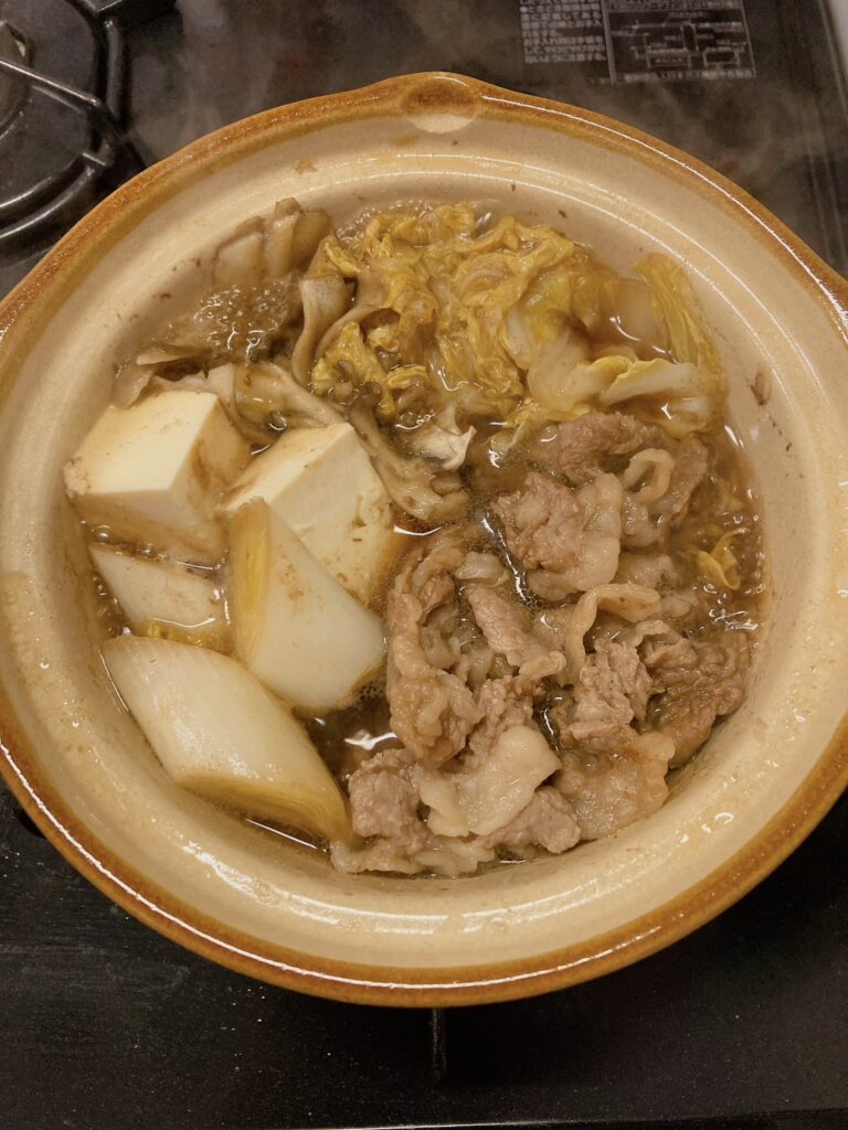 長ネギと牛肉と白菜とまいたけと調味料を煮込んでいる1人用の土鍋