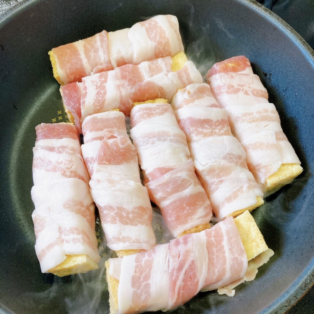 豚バラ肉を巻いた厚揚げを焼いているフライパン