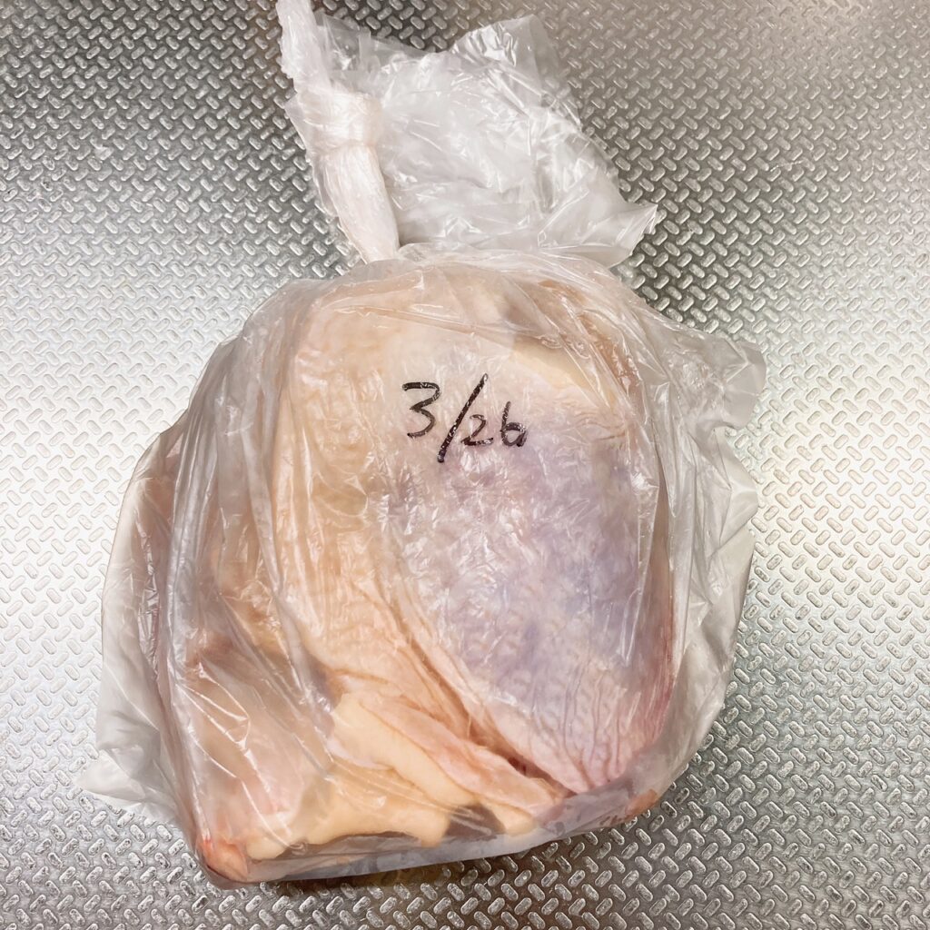 日付が書かれたアイラップに入っている半解凍状態の鶏もも肉1枚