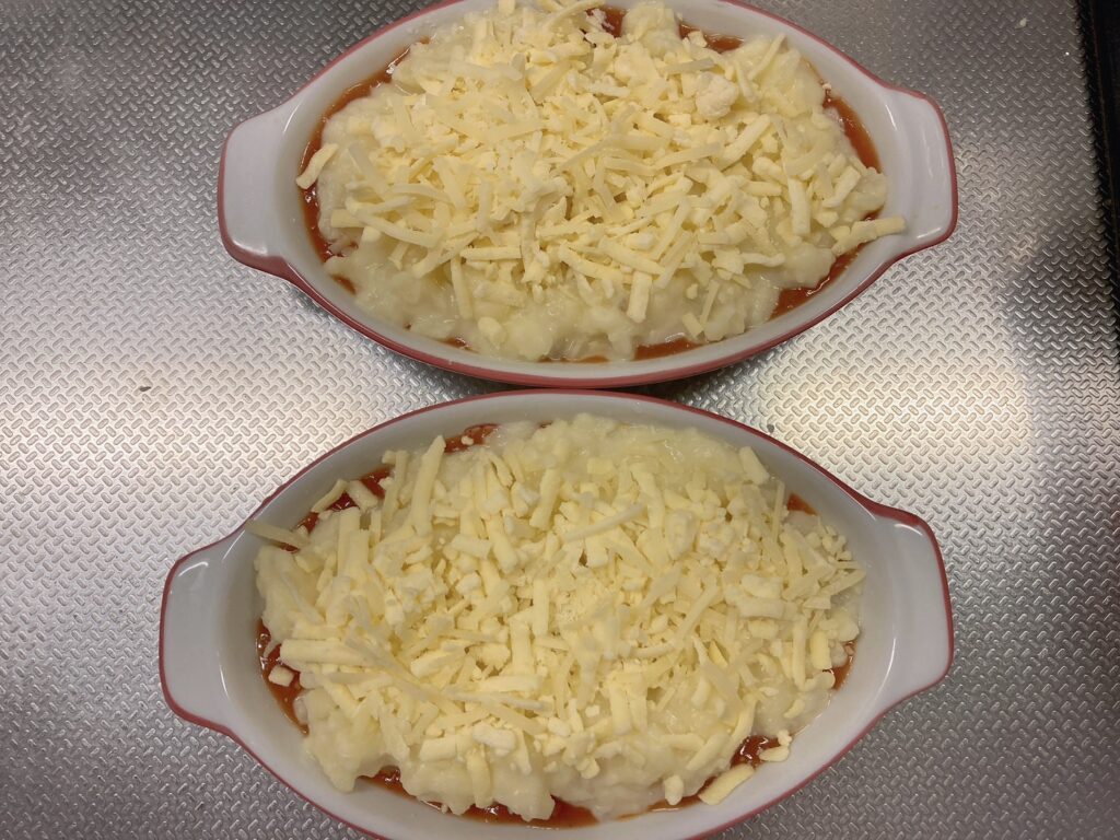 チーズとじゃがいもとレトルトミートソースが入っているグラタン皿2つ