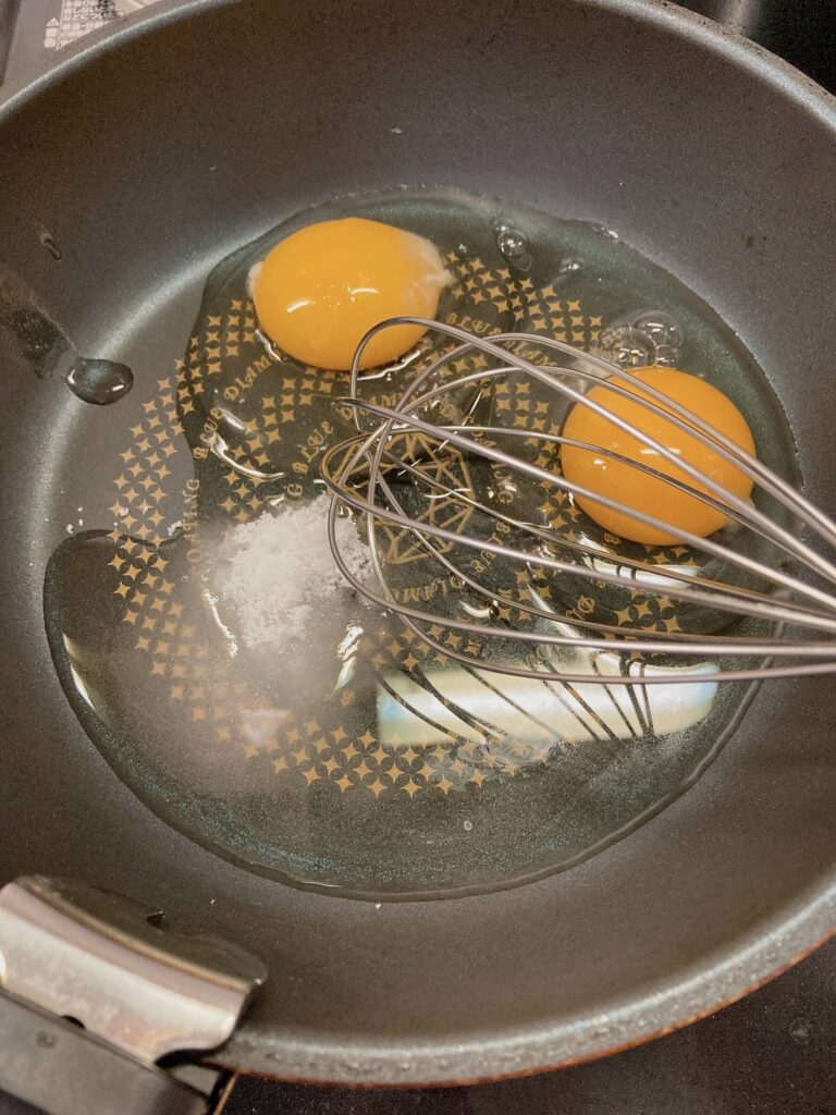 生卵2つと砂糖、酒、塩が入っているフライパン