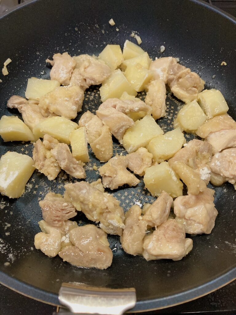 小麦粉と鶏肉とにんにくを炒めているフライパン