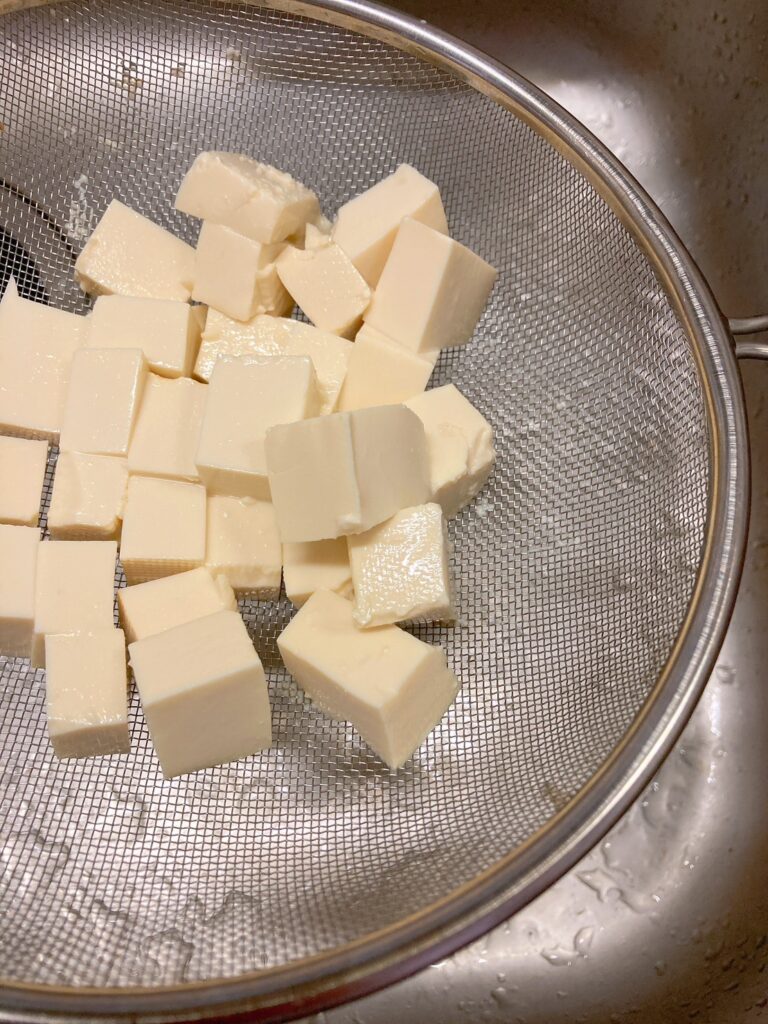 ザルに載せて汁気を切っている1㎝の角切りにした木綿豆腐