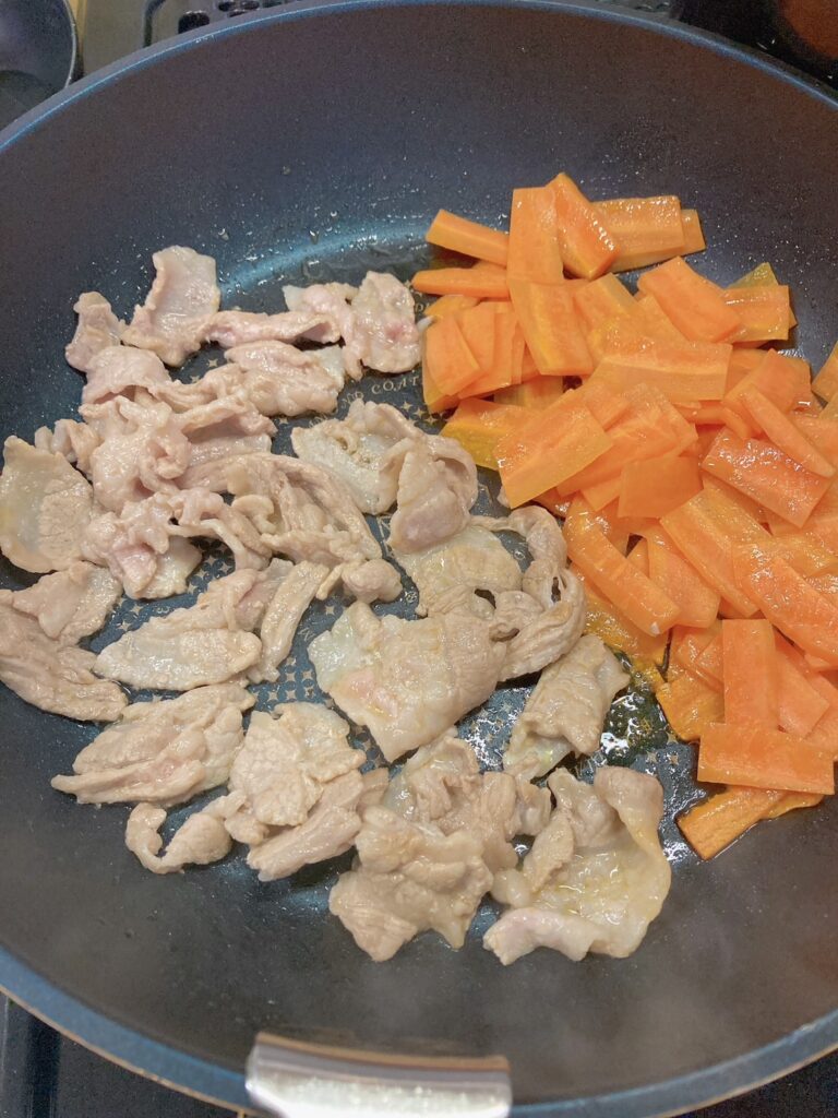 豚バラ肉、にんじんを炒めているフライパン
