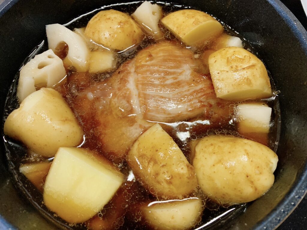 調味料と豚バラブロックとじゃがいもとレンコンを煮ている鍋