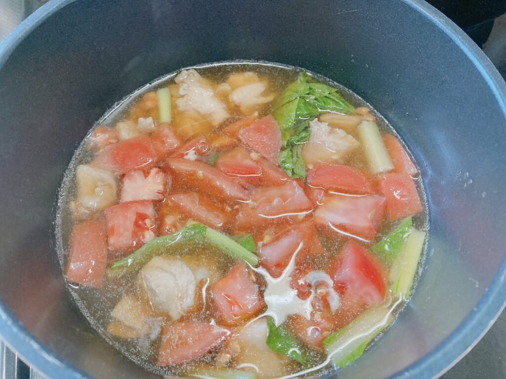 鍋で煮ている鶏肉、トマト、小松菜