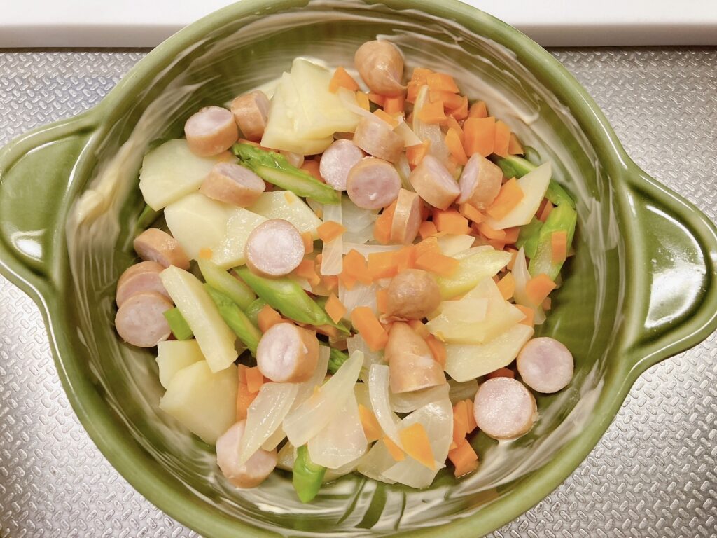 バターが塗られている耐熱皿に入っている野菜とソーセージ